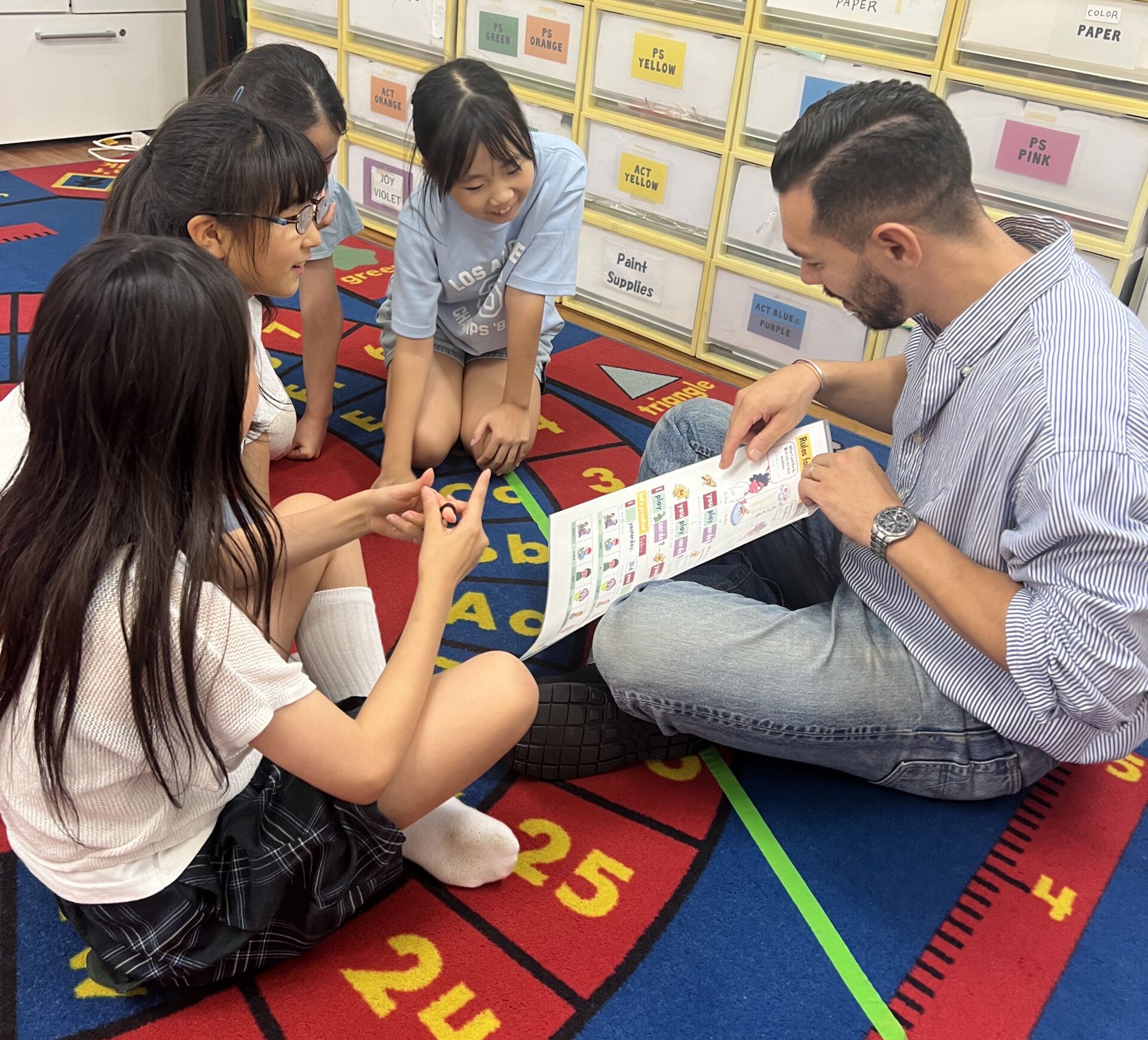 Students learning past tense verb conjugation on the alphabet rug at Seijo Studio