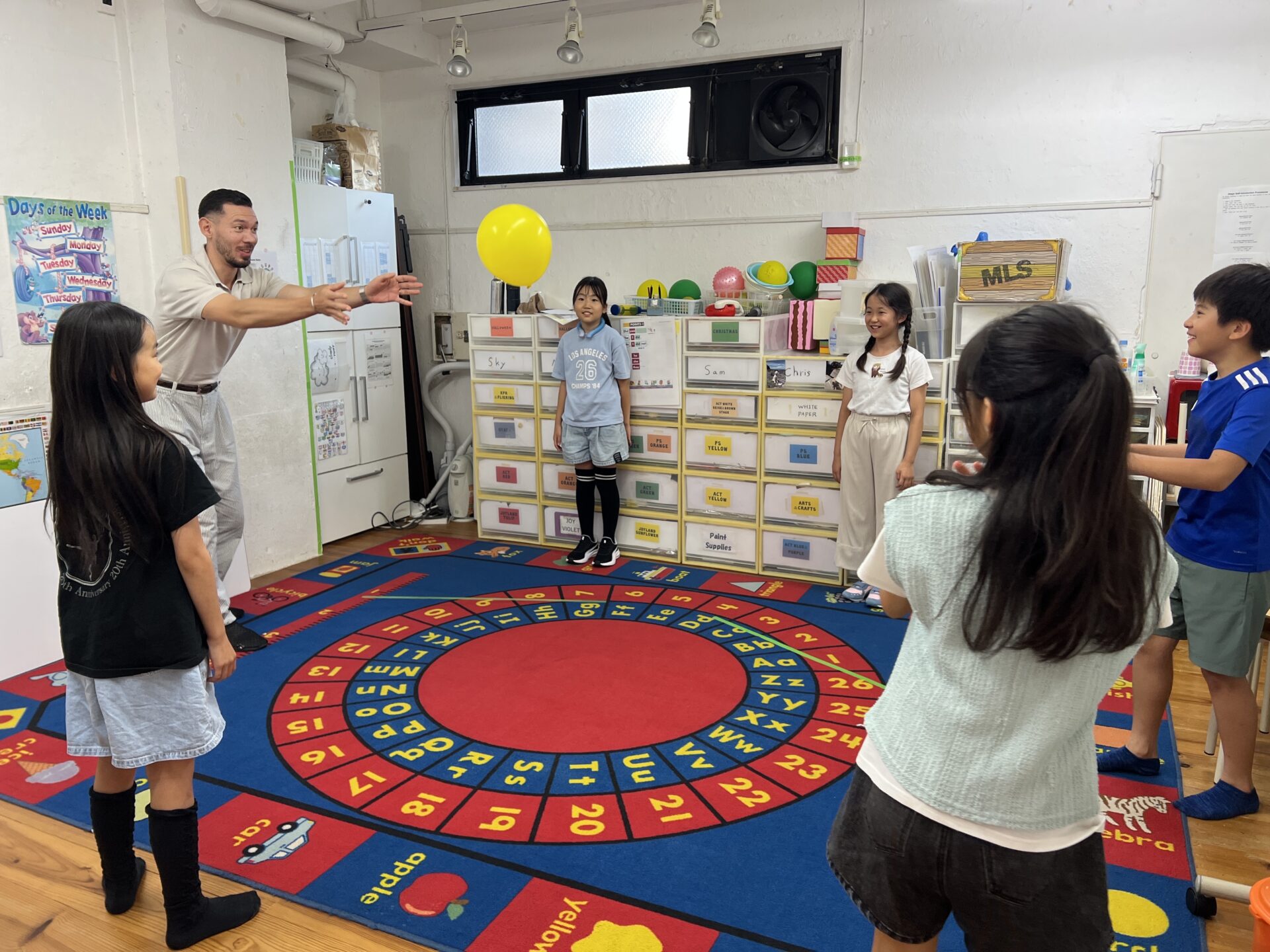 Students learning past tense verb conjugation on the alphabet rug at Seijo Studio